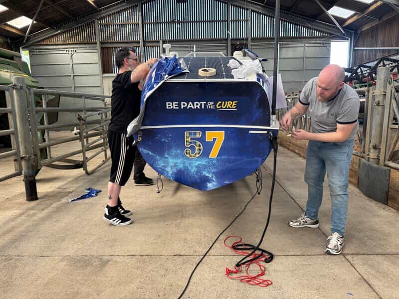 An image of two gentlemen working on applying the vinyl wrap to the boat.